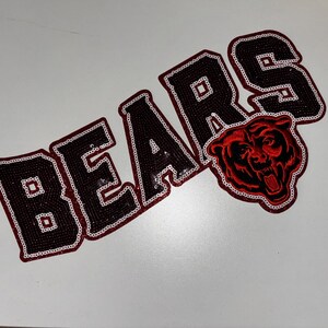 May include: A decorative patch featuring the word BEARS in black sequins with a white sequin outline. The letter R is partially replaced by a red and black embroidered bear head graphic with an open mouth, also outlined in white sequins.