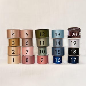 May include: An assortment of satin ribbon spools in various colors, including shades of pink, gold, green, blue, and brown. Each spool is labeled with a number from 1 to 20, indicating different color options for crafting and gift wrapping.