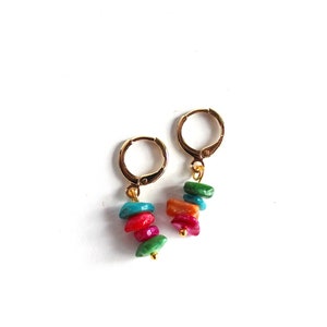May include: A pair of gold hoop earrings with a dangling charm of stacked colorful stones. The stones are green, pink, orange, and red.