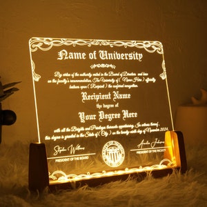 K&ouml;nnte beinhalten: Eine leuchtende Acryl-Plakette mit einem dekorativen Rand und dem Text "Name der Universit&auml;t". Die Plakette steht auf einem Holzst&auml;nder und hat ein Siegel mit dem Text "Pr&auml;sident des Vorstands" und "Pr&auml;sident der Fakult&auml;t".