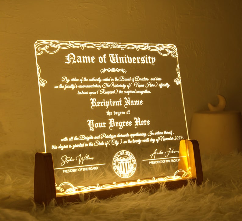 K&ouml;nnte beinhalten: Eine personalisierte, beleuchtete Diplom-Plakette mit einem dekorativen Rand und dem Text "Name of University". Die Plakette zeigt den Namen des Empf&auml;ngers, den Abschluss und das Datum der Graduierung. Der Text "By virtue of the authority vested in the Board of Directors and based on the faculty's recommendation, The University of (Name Here) officially bestows upon (Recipient) the conferred recognition." ist ebenfalls enthalten.