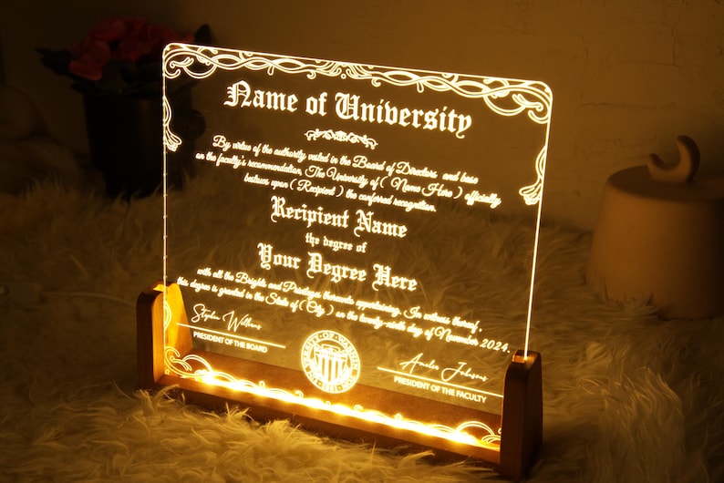 K&ouml;nnte beinhalten: Eine klare Acrylplatte mit einem Holzsockel, von hinten beleuchtet, zeigt eine Vorlage f&uuml;r ein Diplom. Der Text lautet "Name der Universit&auml;t", "Name des Empf&auml;ngers", "Ihr Abschluss hier" und "Pr&auml;sident des Vorstands" und "Pr&auml;sident der Fakult&auml;t".
