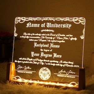 K&ouml;nnte beinhalten: Eine beleuchtete Acryl-Plakette mit goldenem Rahmen, auf der ein Abschlusszeugnis abgebildet ist. Der Text lautet "Name of University" und "Recipient Name" mit dem Abschluss "Your Degree Here". Das Zertifikat ist datiert auf "November 2024".