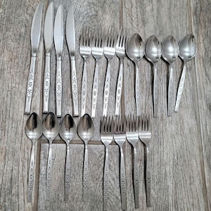 May include: A set of silverware with a floral pattern on the handles. The set includes forks, spoons, and knives.