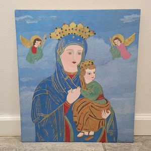 May include: A painting of the Virgin Mary holding baby Jesus. The painting is on a blue background with clouds and two angels. The Virgin Mary is wearing a blue robe with gold trim and a crown of gold and jewels. Baby Jesus is wearing a green robe with a gold crown. The painting is in a folk art style.