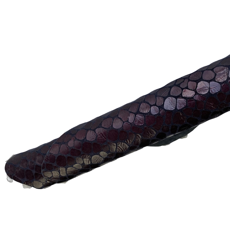 May include: A close-up of a dark purple snakeskin-textured fabric. The fabric has a subtle sheen and a slightly raised texture.