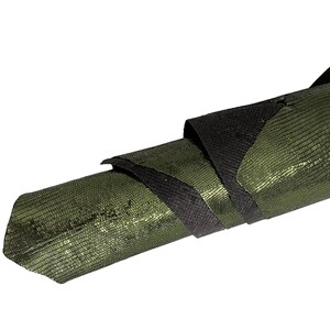 May include: A rolled up piece of green and black textured leather. The leather has a shiny, almost metallic finish.