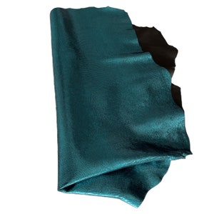 May include: A teal blue leather hide with a textured, scaly surface. The leather is folded in half and appears to be soft and supple.
