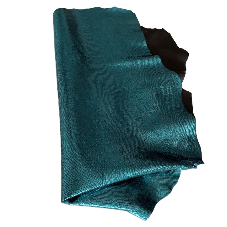 May include: A teal blue leather hide with a textured, scaly surface. The leather is folded in half and appears to be soft and supple.