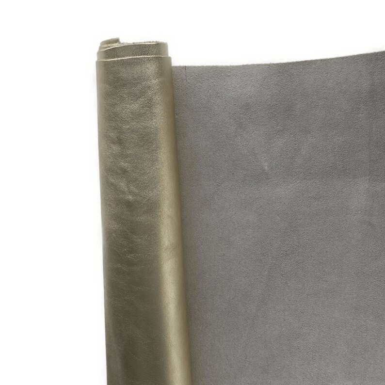 May include: A roll of metallic gold leather with a textured surface, partially unrolled to reveal a gray suede-like backing. The leather is likely used for crafting or upholstery projects.