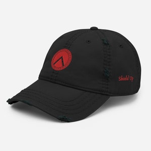 Peut inclure: Casquette de baseball noire usée avec un bouclier brodé rouge avec un triangle blanc à l'intérieur et le texte "Shield Up" en rouge au dos.