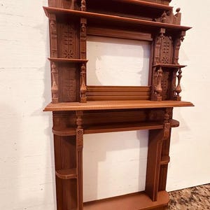 May include: A brown, intricately carved wooden shelf unit. It has multiple shelves and decorative features, including detailed carvings and architectural elements. The unit is designed for display or storage purposes.