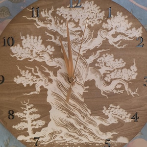 May include: A round wooden clock with a detailed tree design. The clock face is a light brown color, with a white tree illustration and black numbers. The clock hands are made of wood.