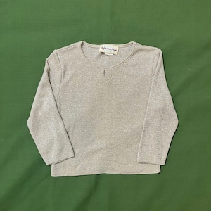 May include: A beige long-sleeved shirt with a small keyhole cutout at the neckline. The shirt has a subtle shimmer and the label "Afternoon Pearl" is visible on the front.