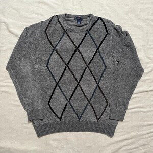 May include: A gray sweater with a black and blue diamond pattern.