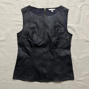 May include: A sleeveless black faux leather top with a zipper closure in the back. The top has a fitted silhouette and a round neckline.