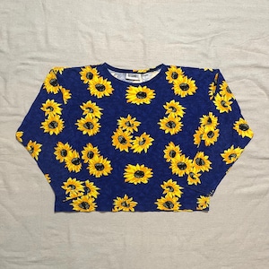 May include: A blue long-sleeved shirt with a sunflower print. The shirt has a crew neck and the brand name "CITAMOE" is visible on the tag.