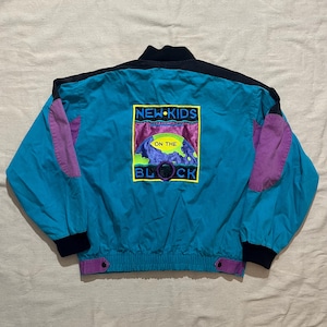 May include: A teal and black vintage jacket with purple accents. The back of the jacket features a colorful graphic with the text "NEW KIDS ON THE BLOCK". The jacket has a black collar and cuffs.