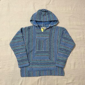 May include: A blue and black striped hooded poncho with a small pocket on the front. The poncho has a yellow tag with the text "Island Style" on it.