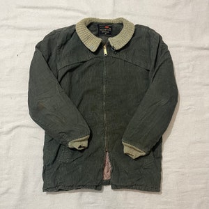 Puede incluir: Chaqueta de pana verde oscuro con cremallera completa y cuello y puños de punto verde claro. La chaqueta tiene un aspecto vintage y una pequeña etiqueta en el cuello que dice "Nortex".