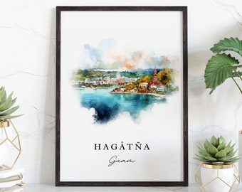 May include: A framed watercolor print of Hagåtña, Guam. The print features a cityscape with buildings and a body of water. The print is framed in a black frame and is hanging on a white wall. There are two potted plants on the shelf below the print.