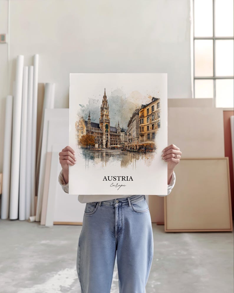 May include: A watercolour print depicting a European city, with a prominent building featuring a spire and other structures in shades of brown, yellow, and grey. The print is labelled "AUSTRIA Europe". The print is held by a person.