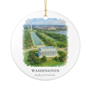 Może przedstawiać: Biała ceramiczna ozdoba świąteczna z akwarelą przedstawiającą Waszyngton, D.C. Obraz zawiera Lincoln Memorial, Pomnik Waszyngtona i basen refleksyjny. Tekst "WASHINGTON District of Columbia" jest wydrukowany na dole. Dołączony jest złoty sznurek.