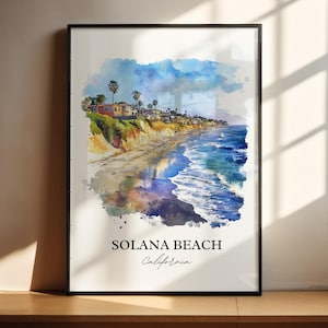May include: Watercolor print of Solana Beach, California, featuring a coastal landscape with houses, palm trees, and ocean waves. The artwork has a black frame and includes the text "Solana Beach California". The color palette includes blues, yellows, and greens.