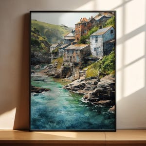 May include: A framed watercolor painting depicts a coastal village nestled along a river. The buildings, with their aged facades, are painted in shades of white, brown, and orange. The water is a vibrant turquoise, and the surrounding cliffs are covered in green vegetation.