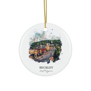 Könnte beinhalten: Runder, weißer Keramik-Weihnachtsschmuck mit einem Aquarellgemälde einer Stadtansicht. Der Schmuck hat eine goldene Aufhängeschnur und den Text "BECKLEY West Virginia". Das Kunstwerk zeigt Gebäude, Bäume und eine Straße.