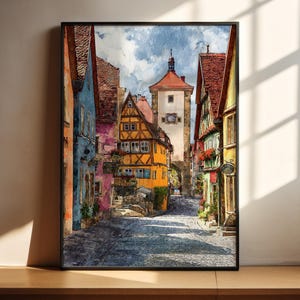Op de afbeelding: Waterverfschilderij van een Europese straatscène met kleurrijke gebouwen en een hoge toren. De gebouwen zijn geschilderd in tinten blauw, oranje, geel en roze. De geplaveide straat leidt naar een toren met een rood dak en een klok.