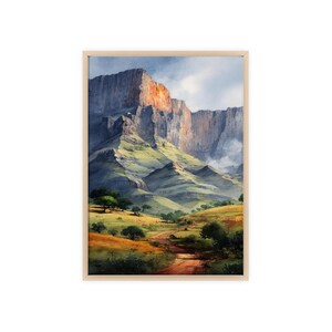 Könnte beinhalten: Gerahmtes Aquarellgemälde einer Berglandschaft. Das Kunstwerk zeigt eine hoch aufragende Felsformation mit rötlich-oranger Färbung, grüne Hügel und einen Feldweg. Der Himmel ist eine Mischung aus Blau und Weiß.