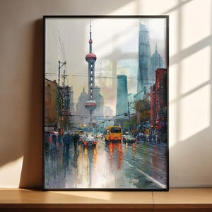 Könnte beinhalten: Ein gerahmtes Aquarellgemälde einer Stadtstraßenszene. Das Kunstwerk zeigt eine nasse Straße, die das Licht von Autos und Gebäuden reflektiert. Ein markanter Turm mit einer roten Kugel befindet sich in der Mitte, mit anderen Wolkenkratzern im Hintergrund. Das Gemälde hat einen schwarzen Rahmen.