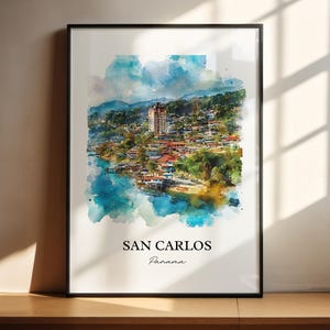 May include: A framed watercolour print of San Carlos, Panama. The artwork shows a coastal town with colourful buildings, green hills, and a blue sea. The text "SAN CARLOS" and "Panama" are printed at the bottom of the print.