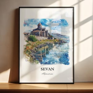 May include: Watercolor painting of a church on a lake in Sevan, Armenia. The church is gray and has a tall steeple. The lake is blue and reflects the sky. The painting is framed in black.