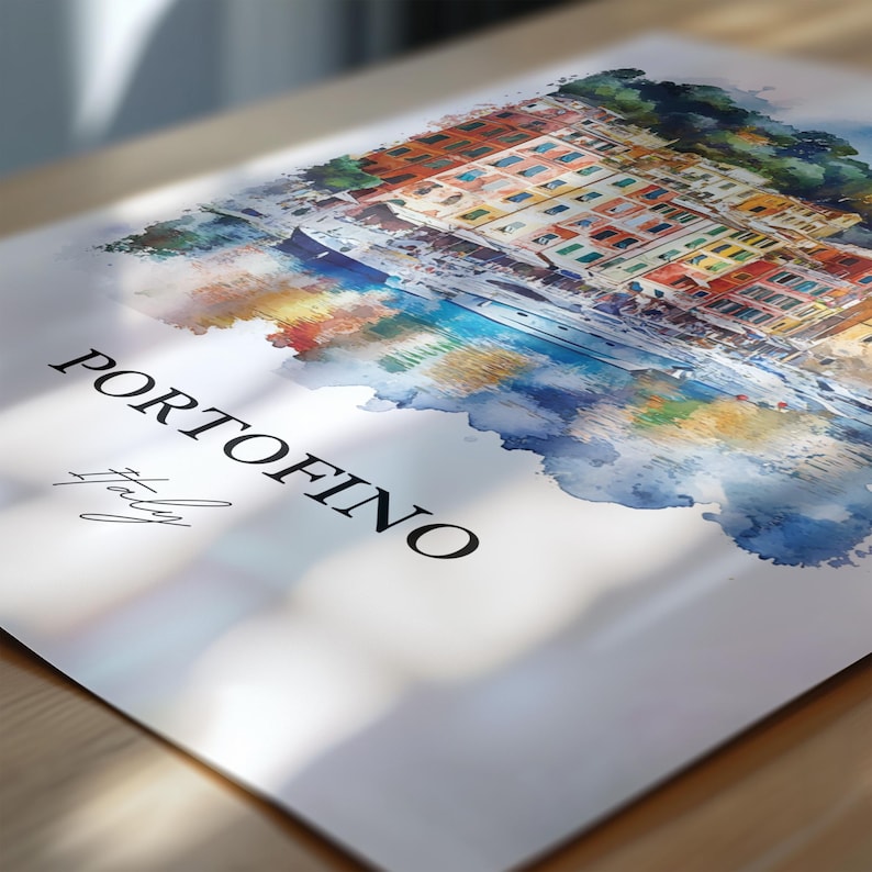 Op de afbeelding: Een aquarel schilderij van de Italiaanse stad Portofino, met kleurrijke gebouwen langs de waterkant. Het schilderij heeft een zachte, dromerige uitstraling, met een blauwe en groene aquarel waslaag op de achtergrond.