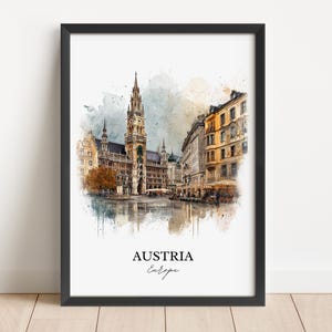 May include: A framed watercolour print depicting a European city, with a prominent clock tower and surrounding buildings. The print is in a black frame, with the words "AUSTRIA" and "Europe" printed at the bottom.