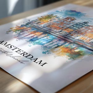 Puede incluir: Una pintura de acuarela de &Aacute;msterdam, Pa&iacute;ses Bajos. La pintura presenta un canal con edificios coloridos que bordean el borde del agua. La pintura est&aacute; rodeada por un lavado de acuarela de azul, verde, naranja y amarillo.