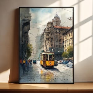 以下が含まれることがあります： ヨーロッパの都市の通りの風景を描いた水彩画。 黄色の路面電車が濡れた通りを走り、歩行者や車が見えます。 建物が通りに並び、電線が空を横切っています。 このアートワークは黒いフレームに入っています。