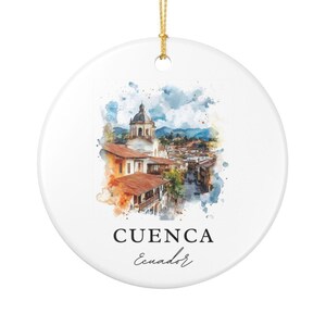 May include: A round white ceramic ornament featuring a watercolor illustration of the city of Cuenca, Ecuador, with terracotta roofs and a prominent church dome. The text CUENCA and Ecuador is printed in black below the colorful cityscape image.