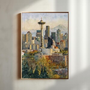 May include: Watercolor painting of the Seattle skyline, featuring the Space Needle and surrounding skyscrapers. The artwork is framed in a gold-colored border and depicts a sunny day with a mountain in the background.