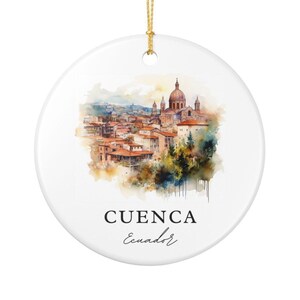 May include: A round white ceramic ornament featuring a watercolor illustration of the city of Cuenca, Ecuador, with terracotta rooftops and a prominent cathedral dome. The text CUENCA Ecuador is printed in black below the painted cityscape.
