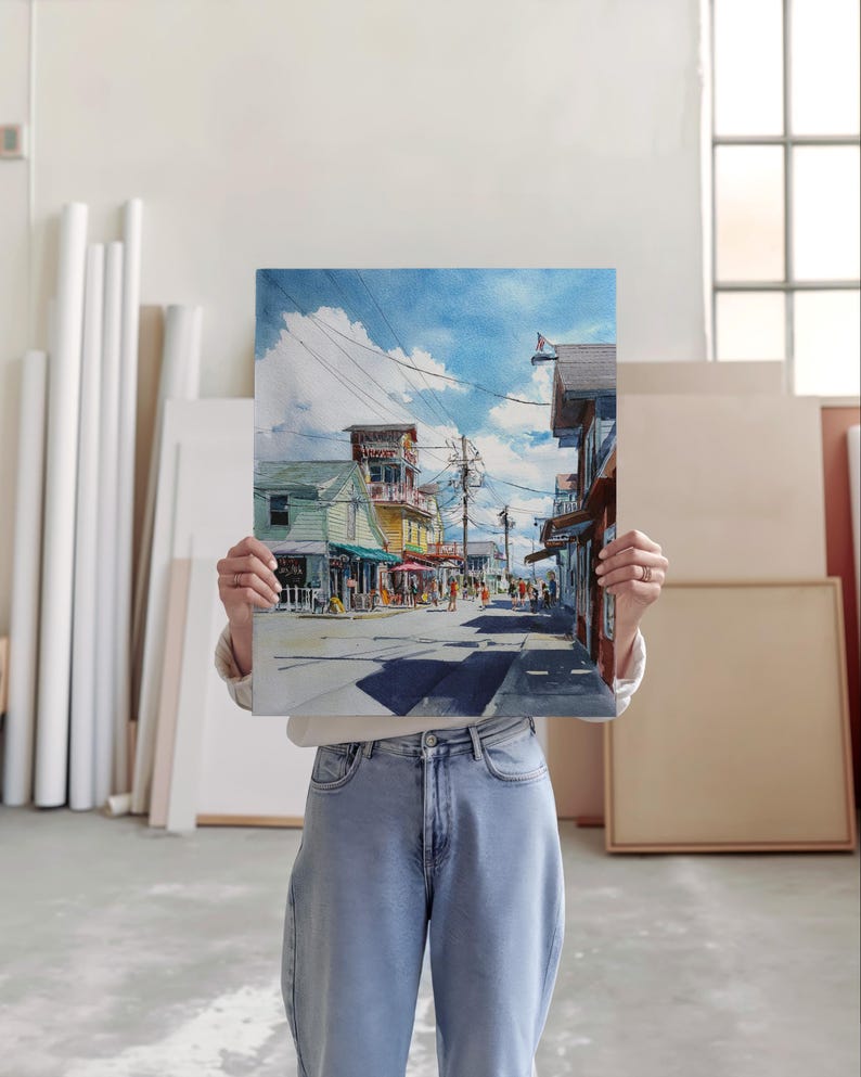 May include: A watercolor painting of a street scene with shops and people. The artwork depicts a sunny day with blue skies and clouds. The buildings are painted in various colors, and the street is lined with people.