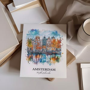 Puede incluir: Una pintura de acuarela de un canal en Amsterdam, Pa&iacute;ses Bajos. La pintura presenta una fila de edificios coloridos con fachadas de ladrillo rojo y &aacute;rboles verdes. El canal se refleja en el agua, que es una mezcla de azul, verde y amarillo.