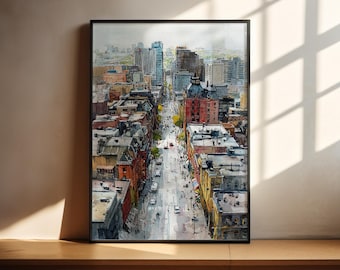 Puede incluir: Impresión artística de un paisaje urbano en acuarela en un marco negro. La obra representa una escena callejera con edificios y coches. Los edificios son de varios colores, incluyendo rojo, marrón y azul. La obra se exhibe sobre una superficie de madera.