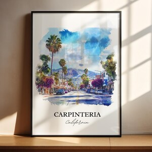May include: A framed watercolor print of Carpinteria, California, featuring a street scene with palm trees, buildings, and cars. The sky is painted with blue and white hues. The text "CARPINTERIA California" is displayed at the bottom.