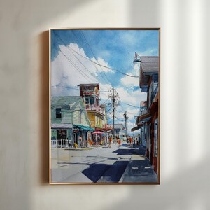 May include: Watercolor painting of a sunny street scene with buildings in various colors, including green, yellow, and red. The sky is blue with fluffy white clouds. People are walking along the street. The artwork is framed in a gold-colored frame.