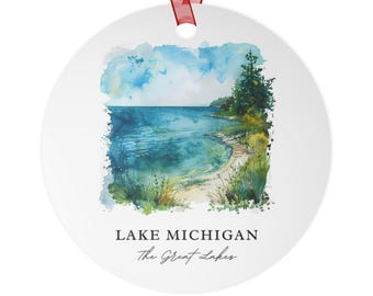 May include: A round white ceramic ornament featuring a watercolour illustration of a blue lake shoreline with green trees and sandy beach. The text reads LAKE MICHIGAN and The Great Lakes in black font. A red ribbon is attached to the top for hanging.