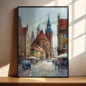Puede incluir: Pintura a la acuarela de una escena de calle de una ciudad europea. La obra presenta edificios con tejados de tejas rojas, una iglesia con una alta aguja y gente caminando por una calle adoquinada mojada. Un coche azul está aparcado en la calle.