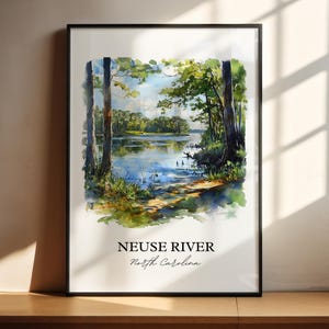 May include: A framed watercolor print of the Neuse River in North Carolina. The artwork depicts a serene landscape with a calm river, lush green trees, and a bright blue sky. The title "Neuse River" and "North Carolina" are printed at the bottom.